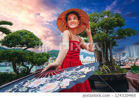 happy young female tourist traveler in Vietnamese non la cone hat and a fan is traveling in Vietnam in Asia 124320468