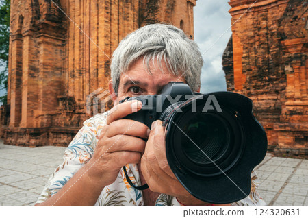 elderly man tourist traveling professional photographer with a camera takes pictures of landmarks at ancient Po Nagar Cham Towers in Nha Trang in Vietnam elderly man tourist traveling professional photographer with a camera takes pictures of landmarks at ancient Po Nagar Cham Towers in Nha Trang in Vietnam 124320631