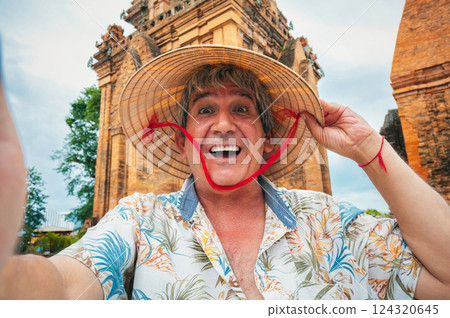 happy elderly male traveler in Vietnamese cone hat non la takes a selfie at Po Nagar Cham Towers in Nha Trang, Vietnam. The concept of travel in Asia happy elderly male traveler in Vietnamese cone hat non la takes a selfie at Po Nagar Cham Towers in Nha Trang, Vietnam. The concept of travel in Asia 124320645