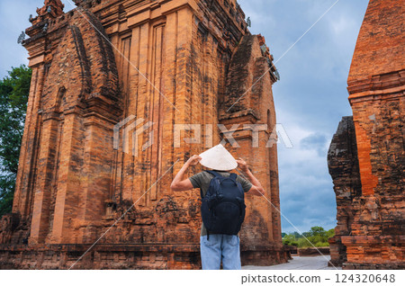 back of Asian male tourist traveler in a Vietnamese cone hat Non La on the Cham Towers of Po Nagar in Nha Trang in Vietnam in Asia back of Asian male tourist traveler in a Vietnamese cone hat Non La on the Cham Towers of Po Nagar in Nha Trang in Vietnam in Asia 124320648