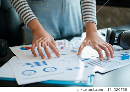 Close-up of hands reviewing financial charts and graphs on a desk, representing business analysis and strategic planning. Close-up of hands reviewing financial charts and graphs on a desk, representing business analysis and strategic planning. 124320766