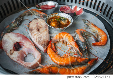 Shrimp and fish are grilled at buffet in an Asian restaurant in Asia in Vietnam. Seafood is fried on the stove Shrimp and fish are grilled at buffet in an Asian restaurant in Asia in Vietnam. Seafood is fried on the stove 124321134