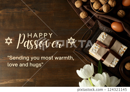Passover, greeting inscription with nuts, flowers, egg, matzah on a tray, on a brown background Passover, greeting inscription with nuts, flowers, egg, matzah on a tray, on a brown background 124321145