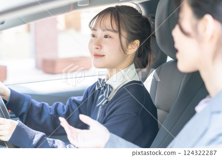 A high school girl learning to drive from an instructor at a driving school A high school girl learning to drive from an instructor at a driving school 124322287