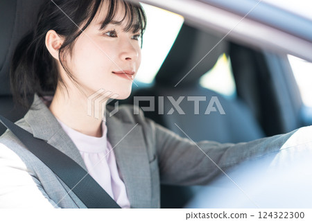 一位身著西裝的年輕女子開著車 124322300