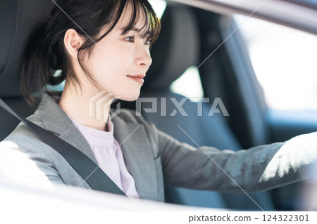 一位身著西裝的年輕女子開著車 124322301