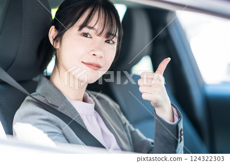 A young woman in a suit in a car making a thumbs up pose A young woman in a suit in a car making a thumbs up pose 124322303