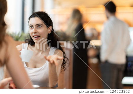 Young woman drinking coffee with her friend in cafe Young woman drinking coffee with her friend in cafe 124323562