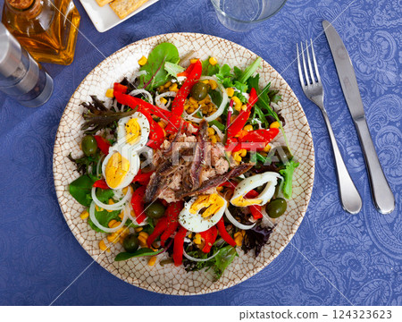 Corn, olive, anchovy, pepper, lettuce salad served on plate 124323623