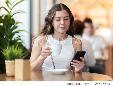 Young woman with phone in cafe 124323644