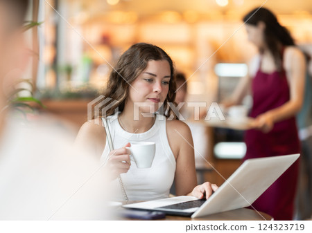 Young woman working at a notebook in a coffee shop 124323719