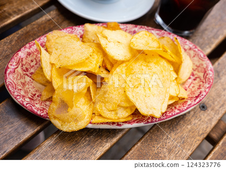 Pile of crispy potato chips on plate served with red vermouth 124323776