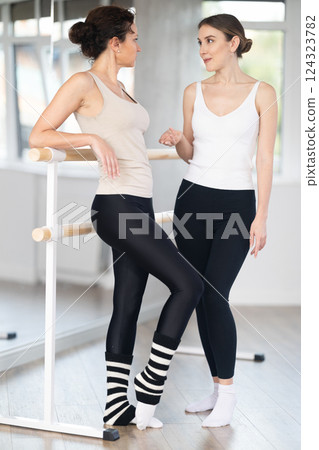 Two women chatting at barre after rehearsal in ballet studio 124323782