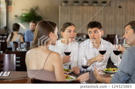 Couples of men and women talking and eating in restaurant 124323865