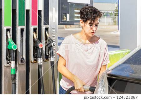 Smiling woman refueling her car in gas station 124323867