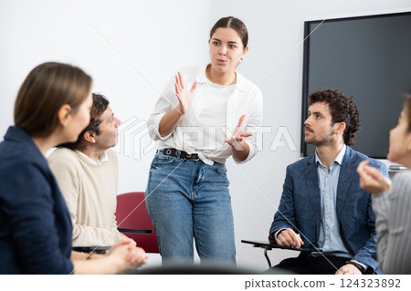 Young female professor explaining subject to classroom full of students 124323892