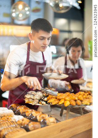 Guy salesperson and girl works in cafeteria bakery shop 124323945