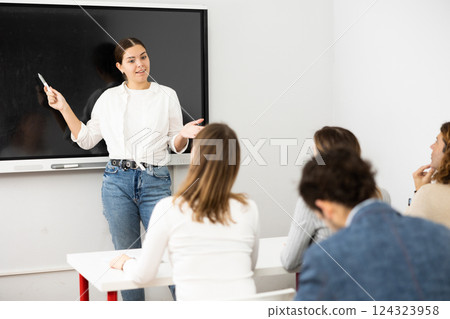 Young female professor explaining subject to classroom full of students 124323958