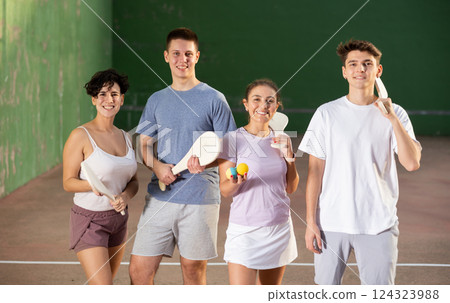 Cheerful pelota players with wooden paletas and rubber balls in outdoor fronton 124323988