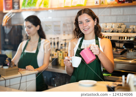 Young woman pouring coffee in cafe 124324006
