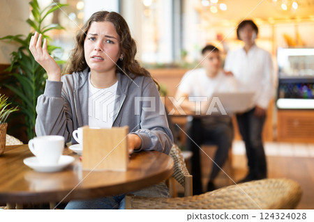 Upset girl resting at table in cafe, drinking coffee Upset girl resting at table in cafe, drinking coffee 124324028