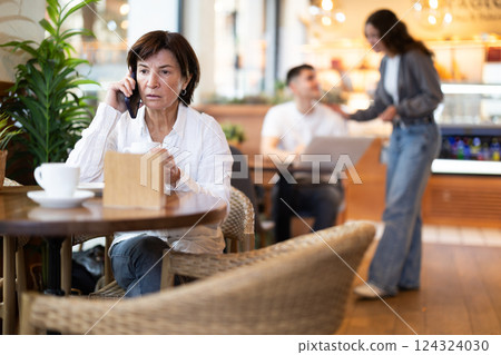 Mature woman talking on the phone in a cafe 124324030