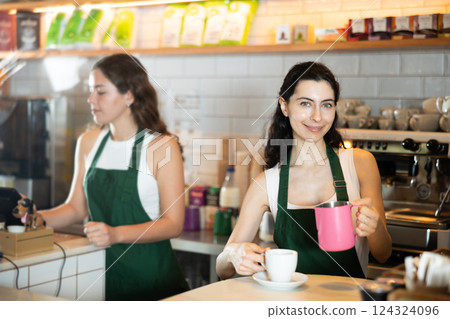 Girl cafe worker pours coffee from cezve coffee pot into cup Girl cafe worker pours coffee from cezve coffee pot into cup 124324096