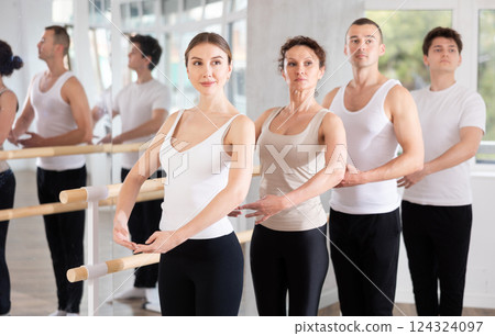 Female ballet student performing first position at barre at group class Female ballet student performing first position at barre at group class 124324097