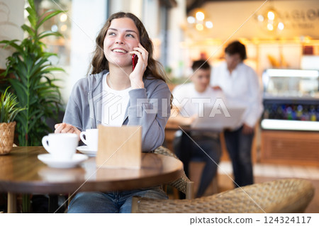 Young woman talking on phone in cafe Young woman talking on phone in cafe 124324117