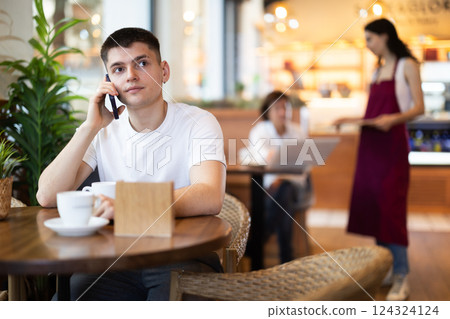 Guy in cafe drinks coffee and calling using mobile phone 124324124