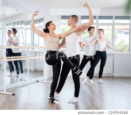 Happy contemporary ballet dancers couple dressed in black and white performing graceful choreography in hall with ballet bar 124324168
