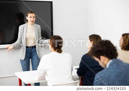 Young female professor explaining subject to classroom full of students 124324183