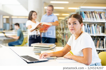 Portrait of woman with laptop and book in public library Portrait of woman with laptop and book in public library 124324207
