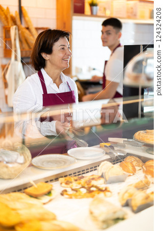 Senior woman salesperson works in cafeteria bakery shop 124324208