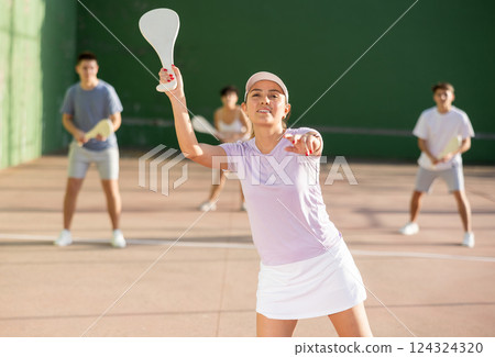 Active womans with enthusiasm playing paleta fronton group on outdoor court 124324320