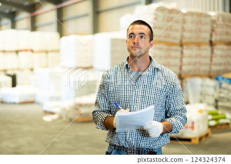 Engineer or foreman holding documents and checking inventory or job details indoor. Engineering site and working with technology concept 124324374
