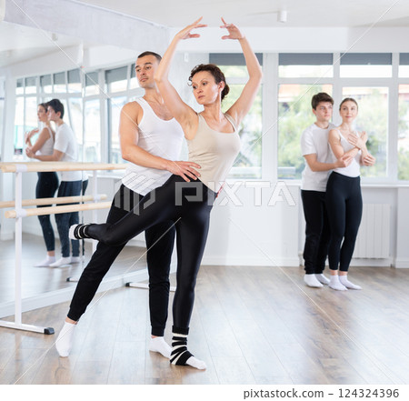 Ballet dancer providing support of female partner in challenging movements Ballet dancer providing support of female partner in challenging movements 124324396