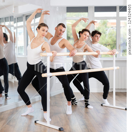 Woman performing demi plie with side lean at barre workout Woman performing demi plie with side lean at barre workout 124324405