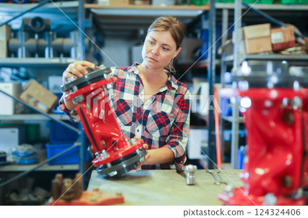 Woman assembling plumbing fixture in workshop Woman assembling plumbing fixture in workshop 124324406