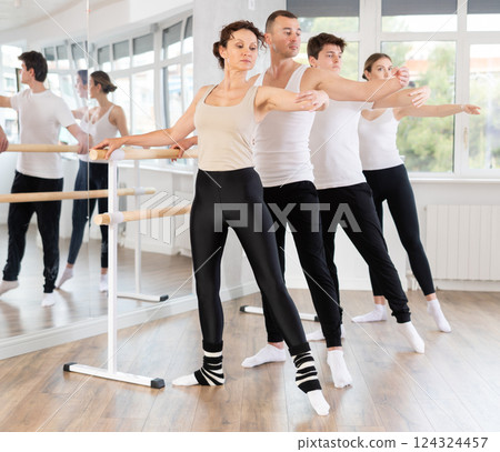 Group of dancers doing batman tandu jete at barre Group of dancers doing batman tandu jete at barre 124324457