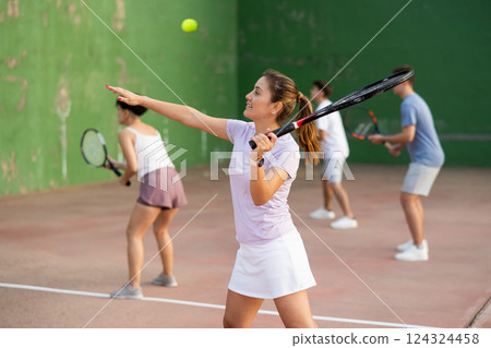 Young hispanic female frontenis player swinging racquet to hit ball 124324458