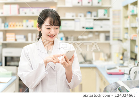 Female pharmacist holding a smartphone (medicine notebook, app, prescription, mobile) 124324665