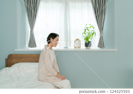 Middle-aged woman sitting on bed 124325503