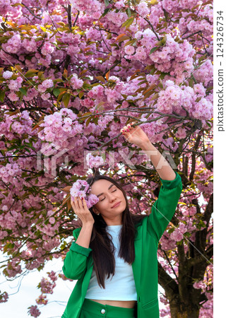 Beautiful woman with eyes closed enjoys the cherry tree flower scent Beautiful woman with eyes closed enjoys the cherry tree flower scent 124326734