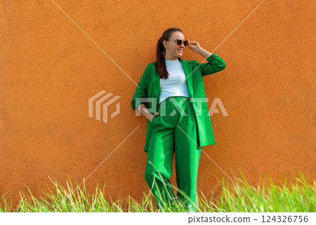 Happy young businesswoman in a green suit and sunglasses on a sunny day 124326756