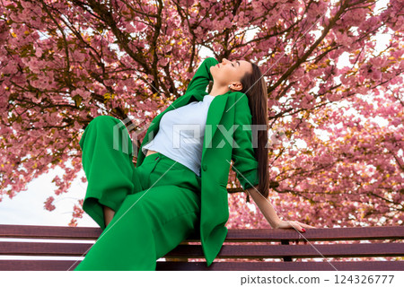 Woman relaxing on a bench under a full bloom cherry tree Woman relaxing on a bench under a full bloom cherry tree 124326777