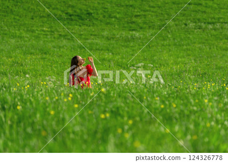 Woman sitting in a meadow in the warm sunset light Woman sitting in a meadow in the warm sunset light 124326778