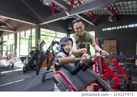 Arab middle eastern muslim woman on bench press training with an indonesian southeast asian personal trainer man at the gym. Fitness exercise and healthy lifestyle concept Arab middle eastern muslim woman on bench press training with an indonesian southeast asian personal trainer man at the gym. Fitness exercise and healthy lifestyle concept 124327475