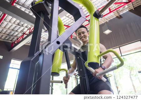 Indonesian southeast asian man training on chest press machine at the gym. Fitness exercise and healthy lifestyle concept 124327477