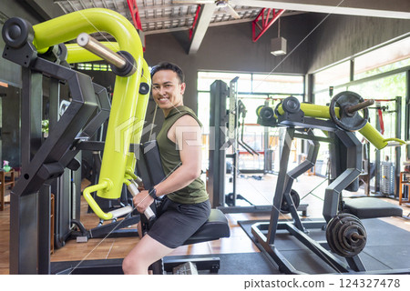 Indonesian southeast asian man training on chest press machine at the gym. Fitness exercise and healthy lifestyle concept 124327478